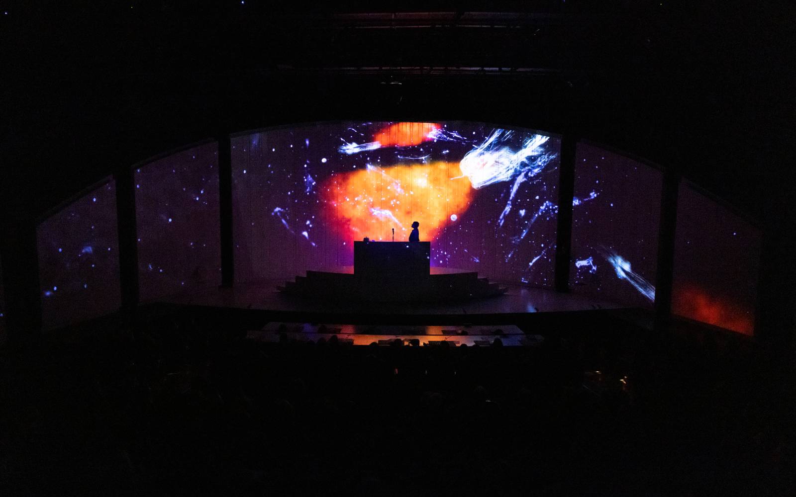 Jennifer Kidwell in Ocean Filibuster, standing against galaxy-like projections.