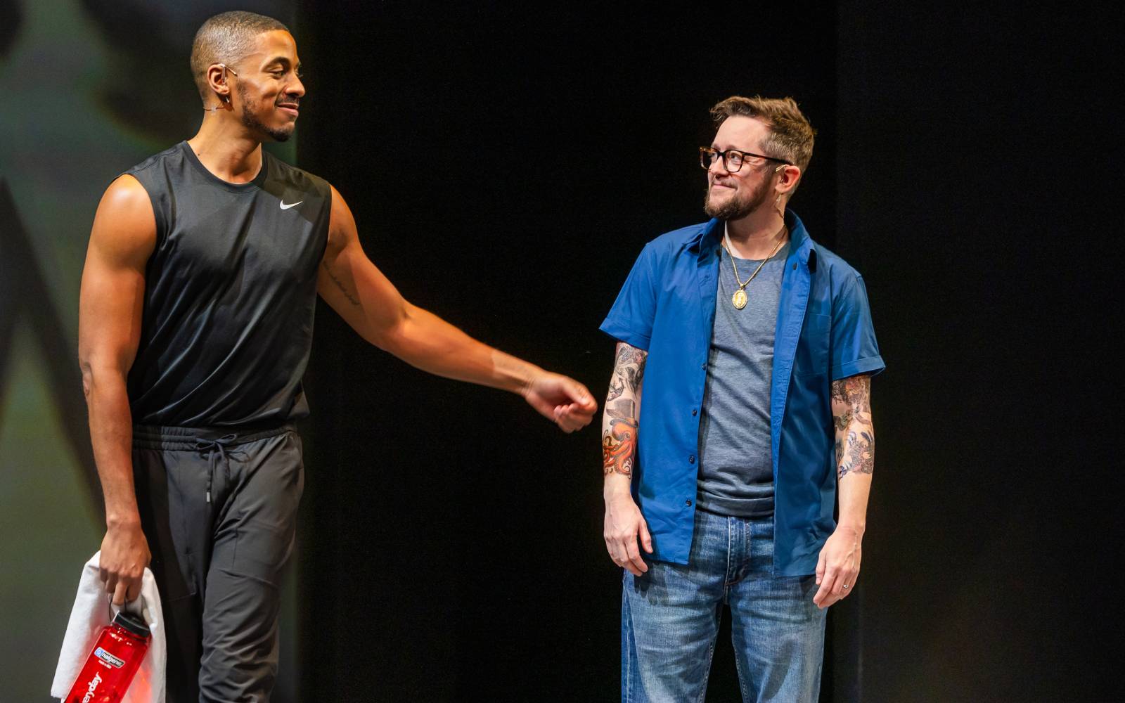 Justiin Davis in black athletic clothes and Petey Gibson in a blue button-down shirt smile at each other.